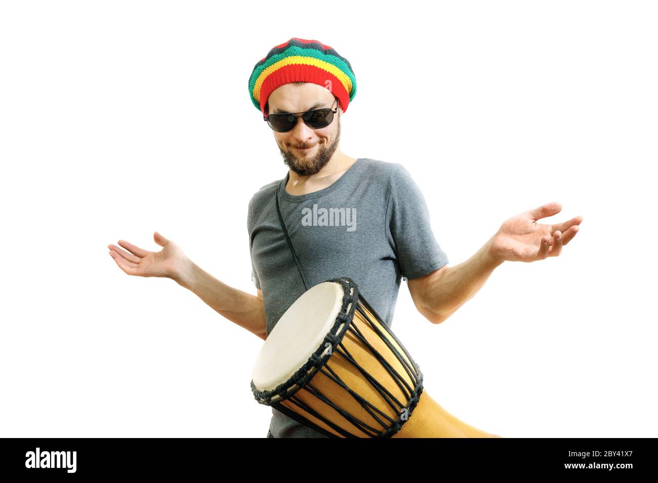 Young handsome guy learns to play the djembe drum instrument on a white