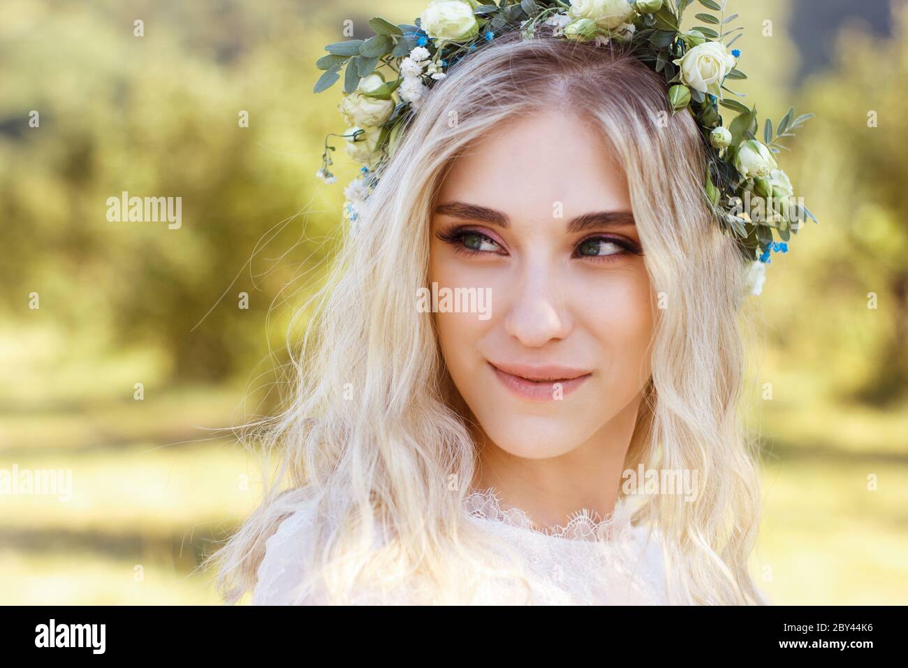 Beautiful Blonde Young Bride Portrait With Flower Bouquet And Wreath On Her Head In White