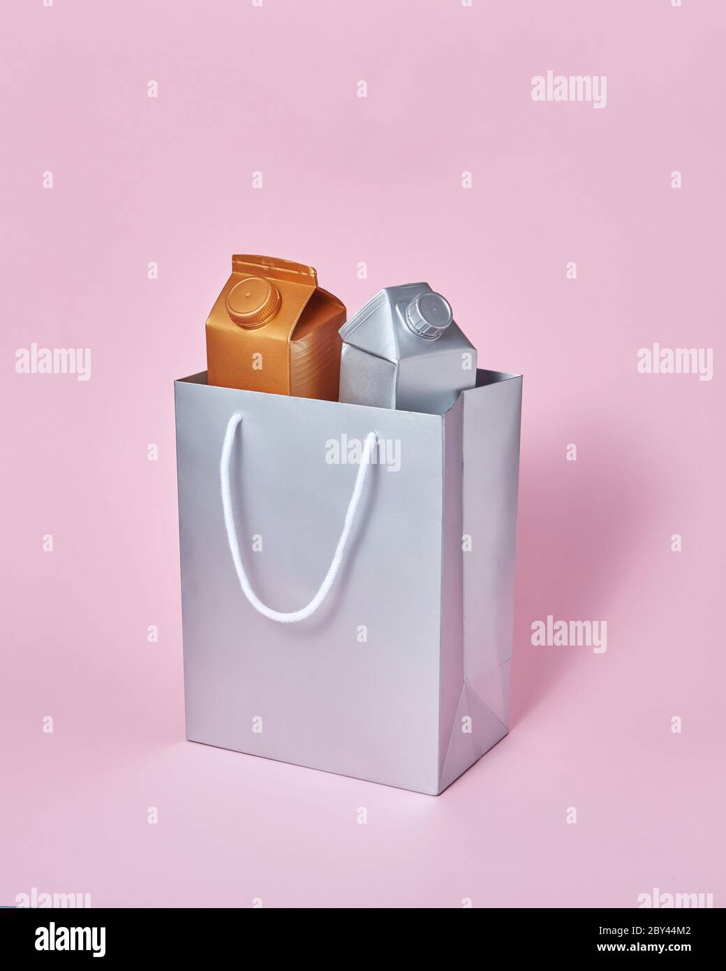 Mock-up silver paper bag with two milk packages on a pink background ...