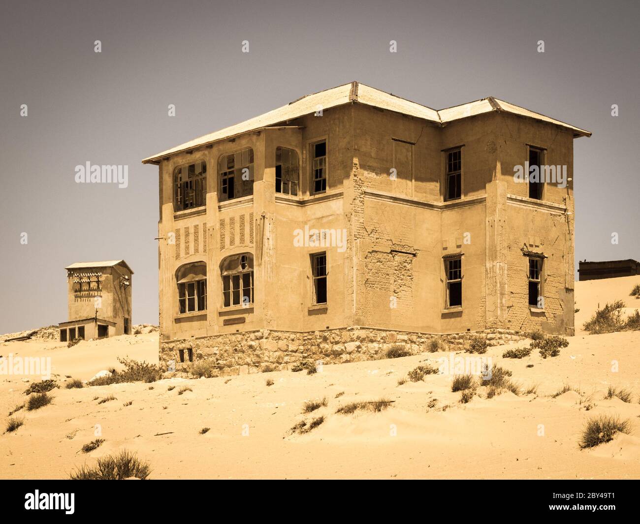 Ghost buildings of old diamond mining town Kolmanskop near Luderitz in Namibia. Abandoned house ruins sunken in the sand dunes of Namib Desert. Vintage toning photography. Stock Photo