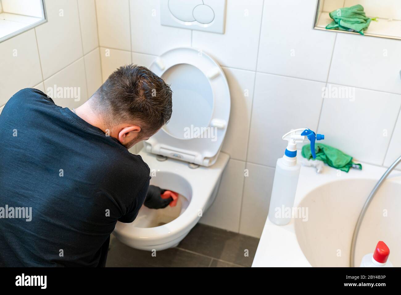 A professional cleaner cleans a ceramic toilet very thoroughly in a ...