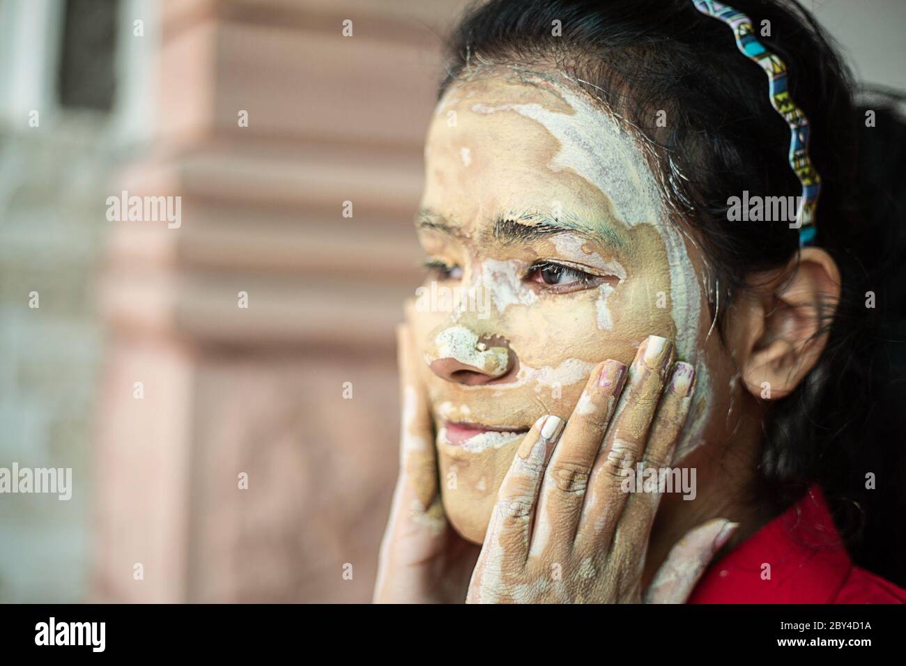 Young brunette girl message ayurvedic natural hearbal cosmetic facial mask applied over her face. multani mitti/fuller earth clay Pack copy space Stock Photo