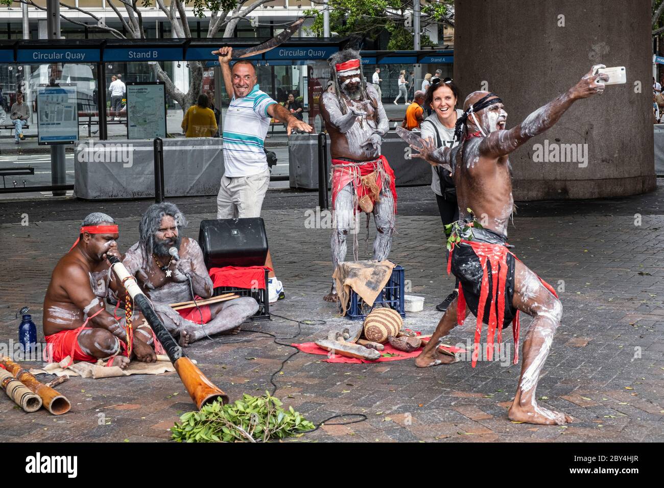 Tourists posing for a photo with aboriginal street performers, Circular Quay, Sydney, New South Wales, Australia Stock Photo