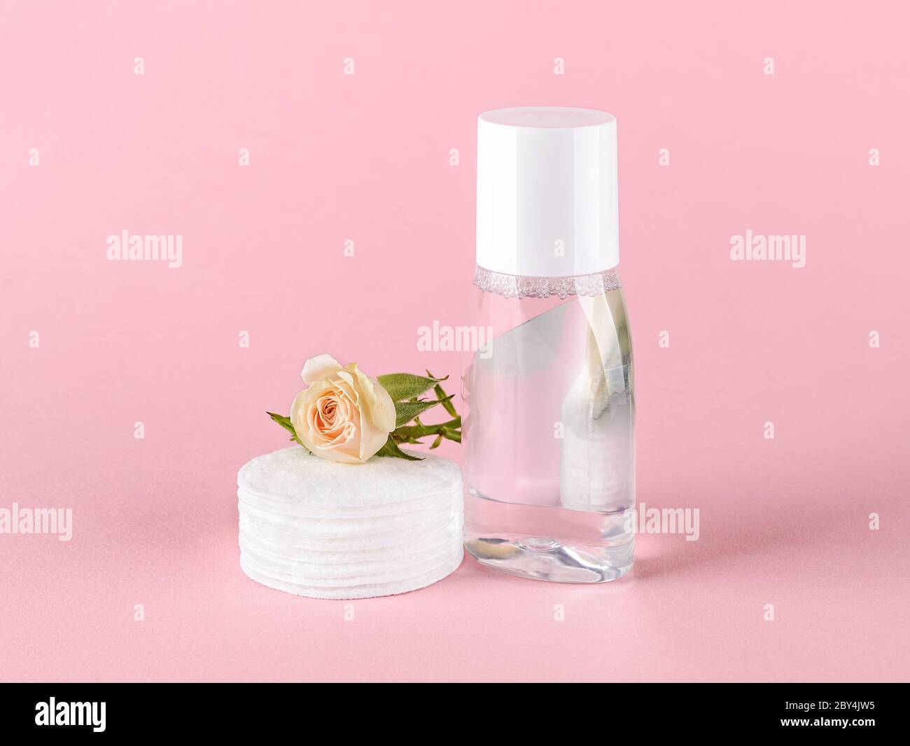 Skin tonic lotion or micellar water, cotton pads and small rose flower