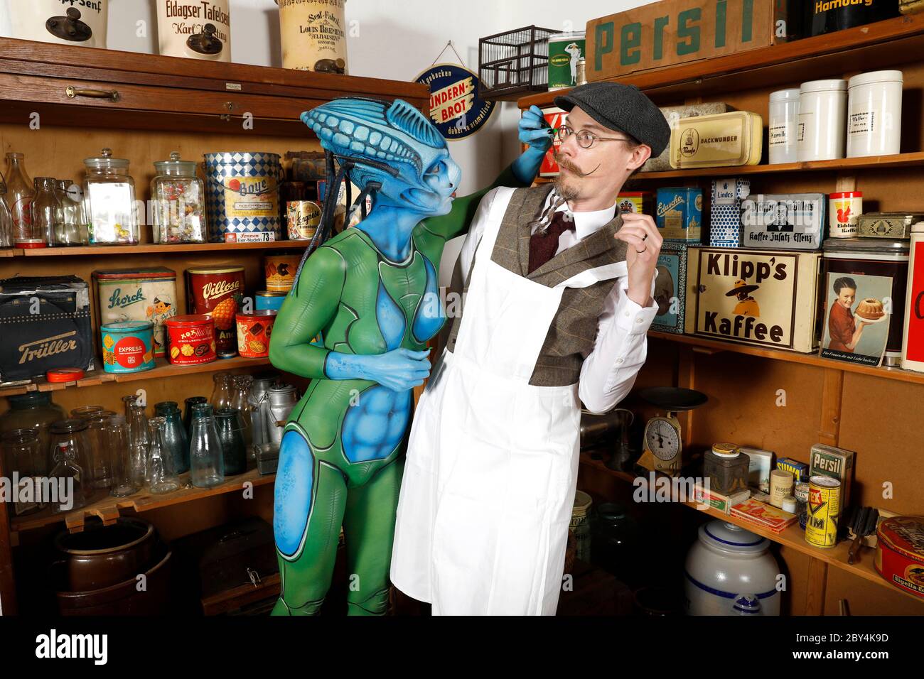 GEEK ART - Bodypainting and Transformaking: 'Aliens visit a shop on earth' with Barbara as visitor and Collin as a seller in a grocery store in the 1950s. Photographed in the village museum of the Tundirum association in Tuendern on June 7, 2020 - A project by photographer Tschiponnique Skupin and bodypainter Enrico Lein Stock Photo