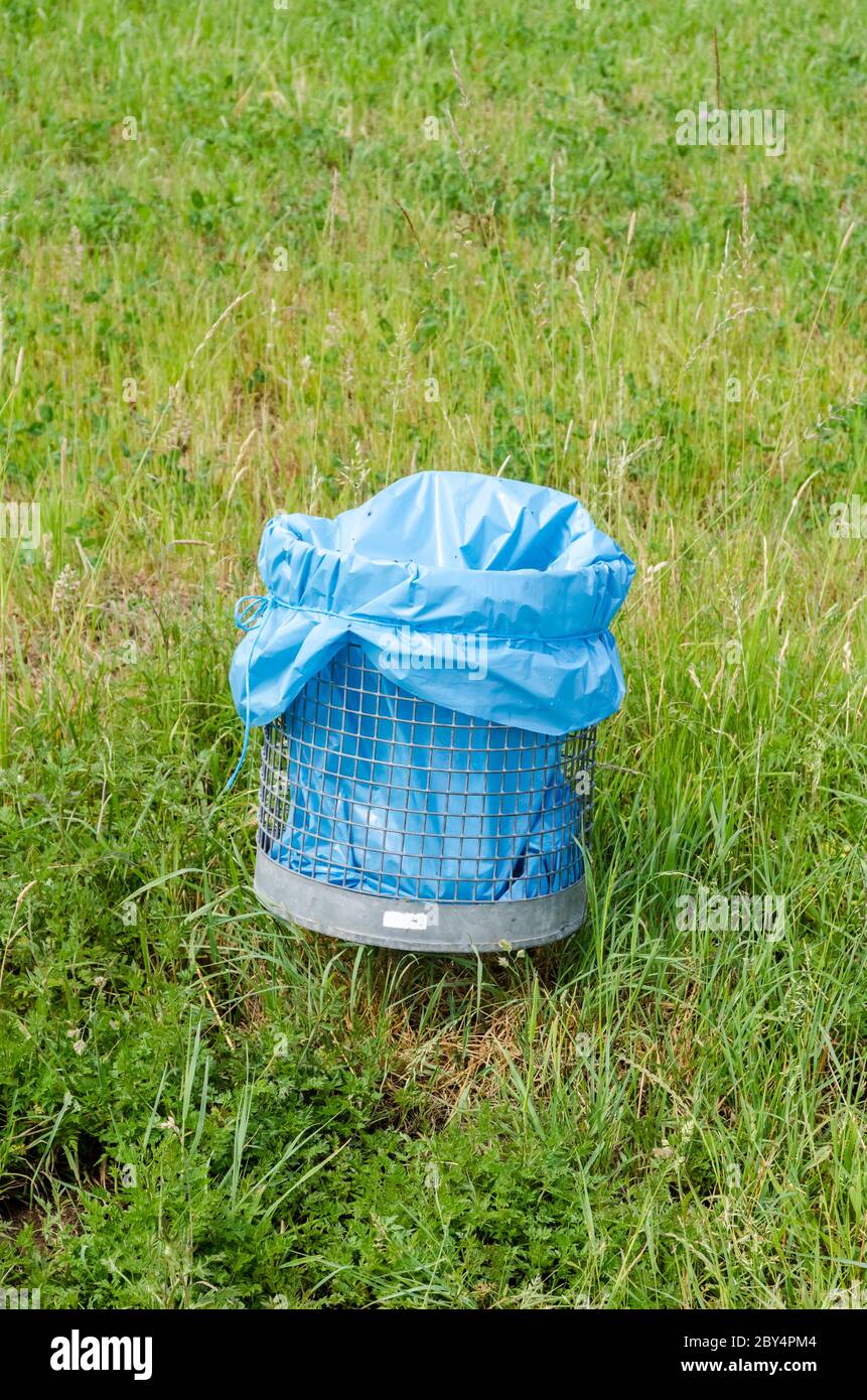 Waste or trash litter bin with blue plastic bag in the rural