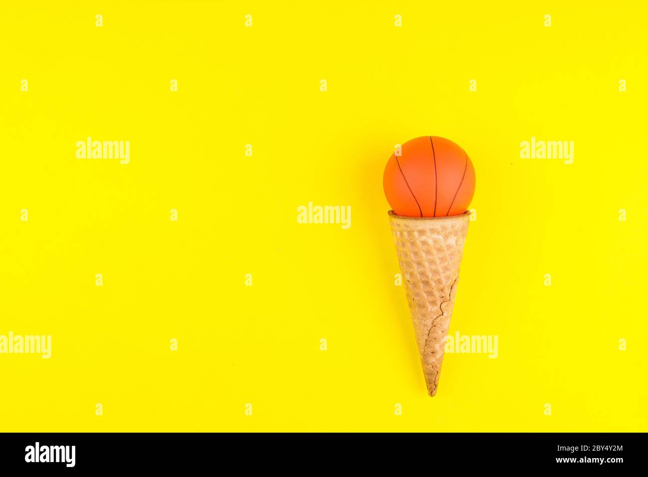 https://c8.alamy.com/comp/2BY4Y2M/basketball-ball-toy-in-ice-cream-waffle-cone-on-yellow-background-in-minimal-style-concept-sports-entertainment-top-view-copy-space-template-for-tex-2BY4Y2M.jpg