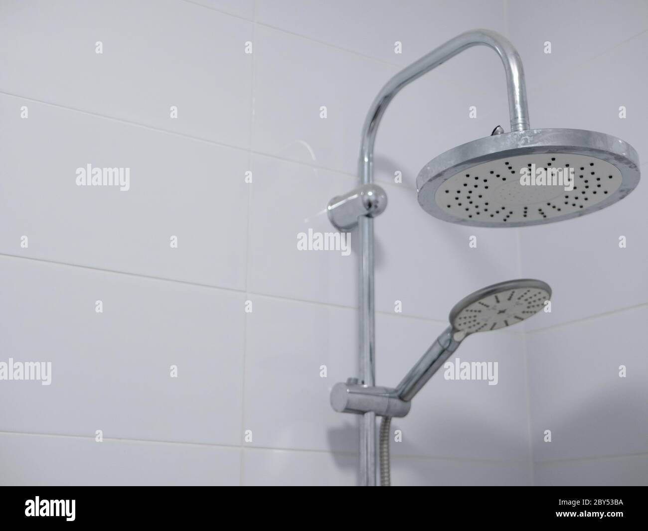 https://c8.alamy.com/comp/2BY53BA/double-shower-heads-with-chrome-finish-in-clean-bathroom-with-pure-white-ceramic-tiles-close-upimage-with-copy-space-2BY53BA.jpg