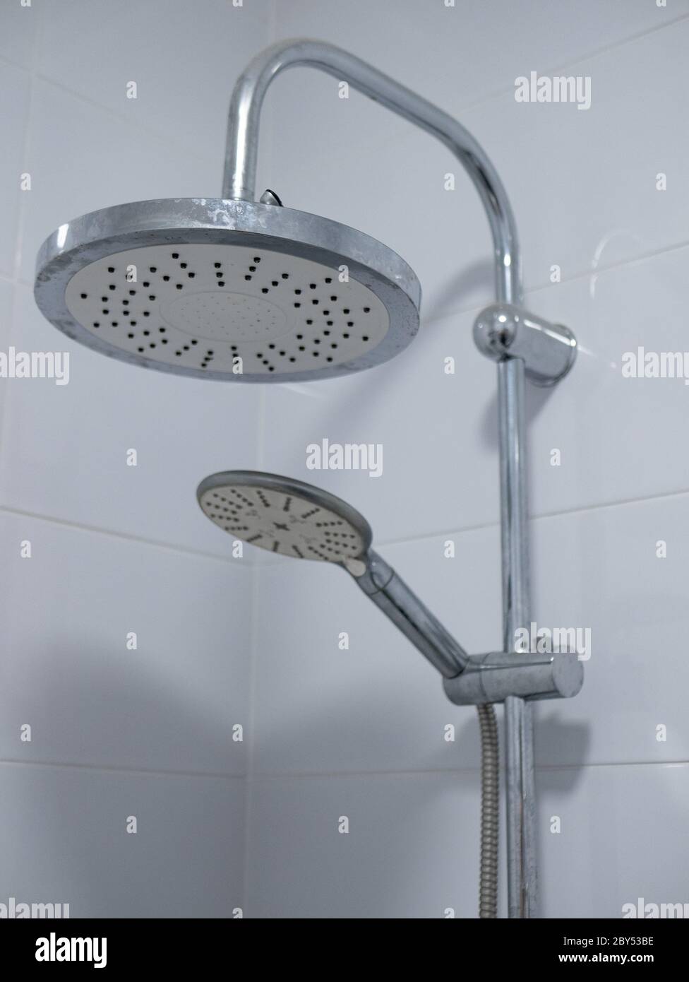 https://c8.alamy.com/comp/2BY53BE/close-up-image-of-two-shower-heads-in-white-tile-bathroom-large-is-mounted-on-metal-pipe-and-small-attached-to-flexible-hose-2BY53BE.jpg