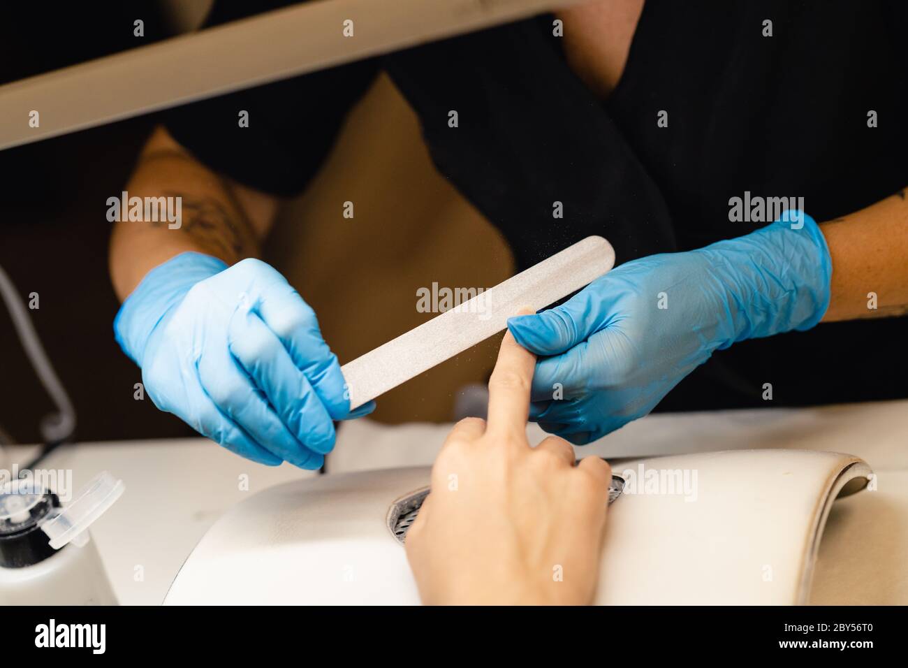 Aesthetician doing the manicure, filing the nails with a file to his client in a beauty center. Business and beauty concepts Stock Photo