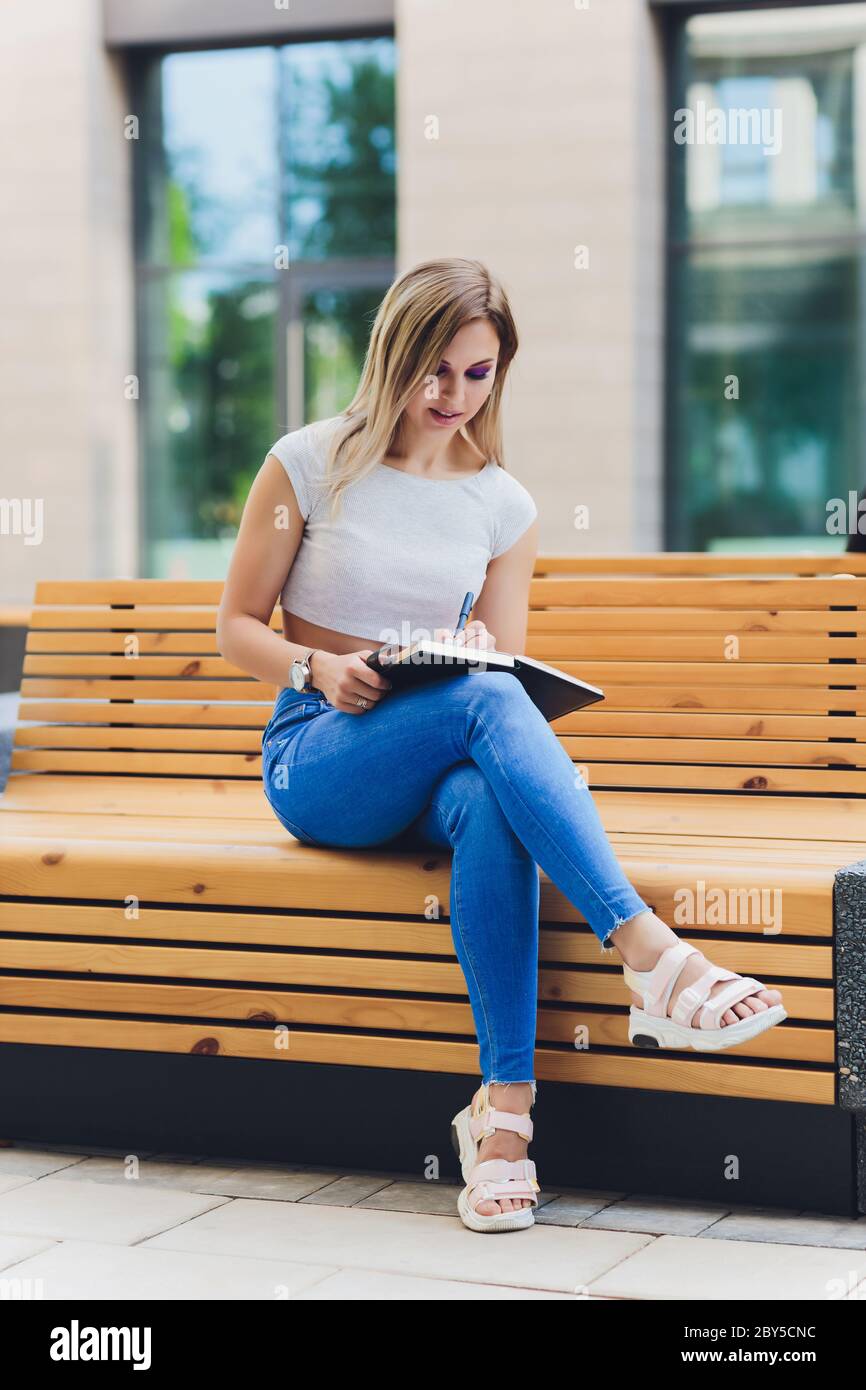 girl writes in a notebook, sitting on a bench in the Park Stock Photo ...