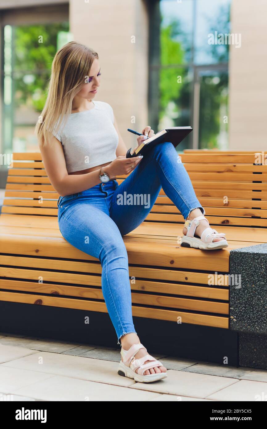 girl writes in a notebook, sitting on a bench in the Park Stock Photo ...