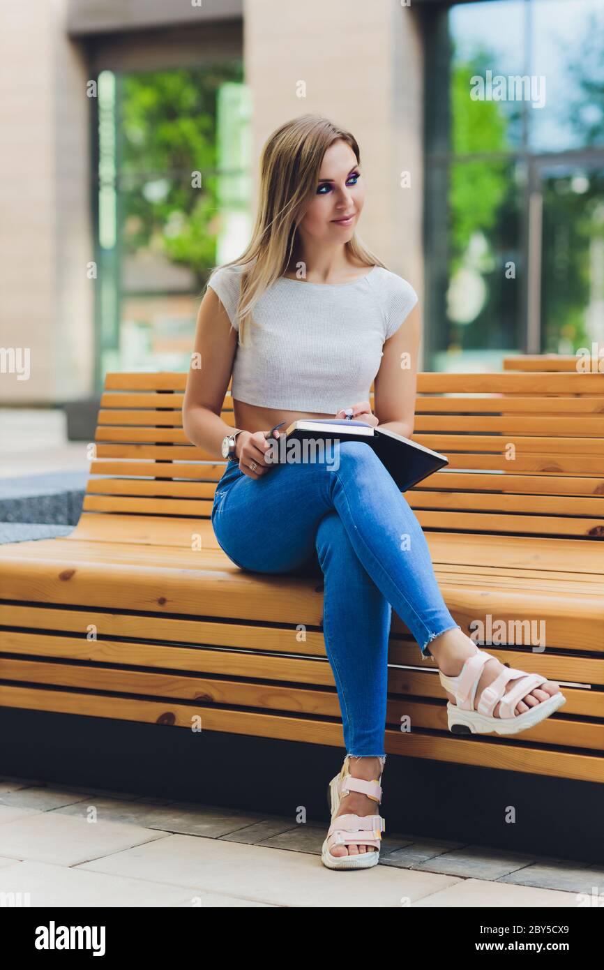 girl writes in a notebook, sitting on a bench in the Park Stock Photo ...
