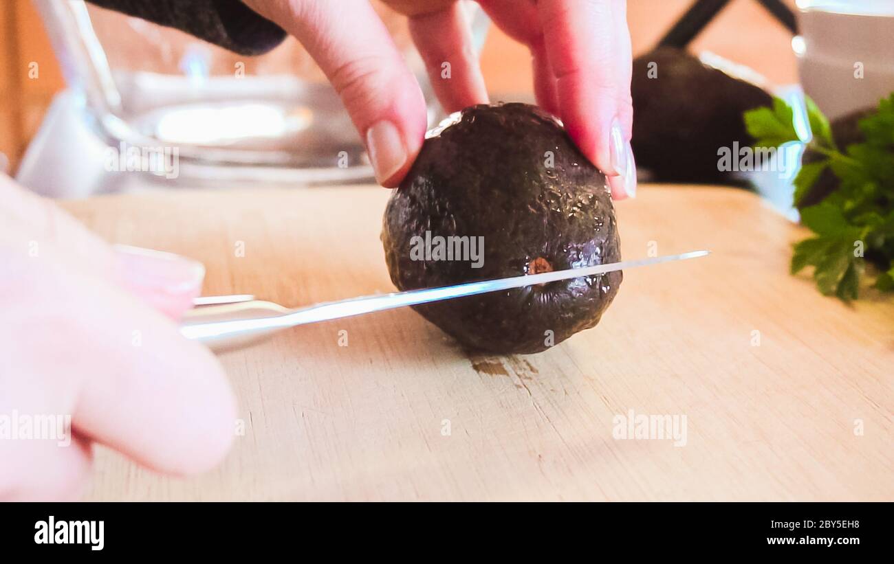 Slicing organic avocado on wood cutting board Stock Photo - Alamy