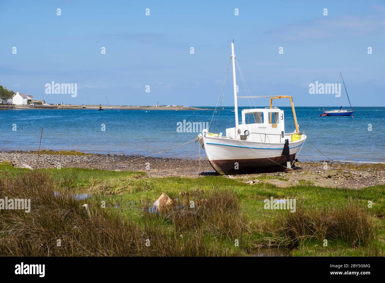 White boat grounded on sea shore in Red Wharf Bay, Isle of Anglesey, Wales, UK, Britain Stock Photo