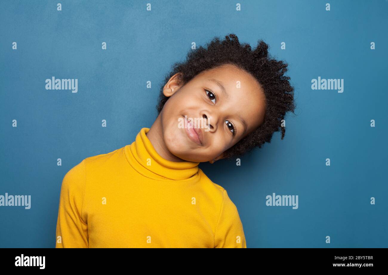 Curious black child boy smiling on blue background Stock Photo