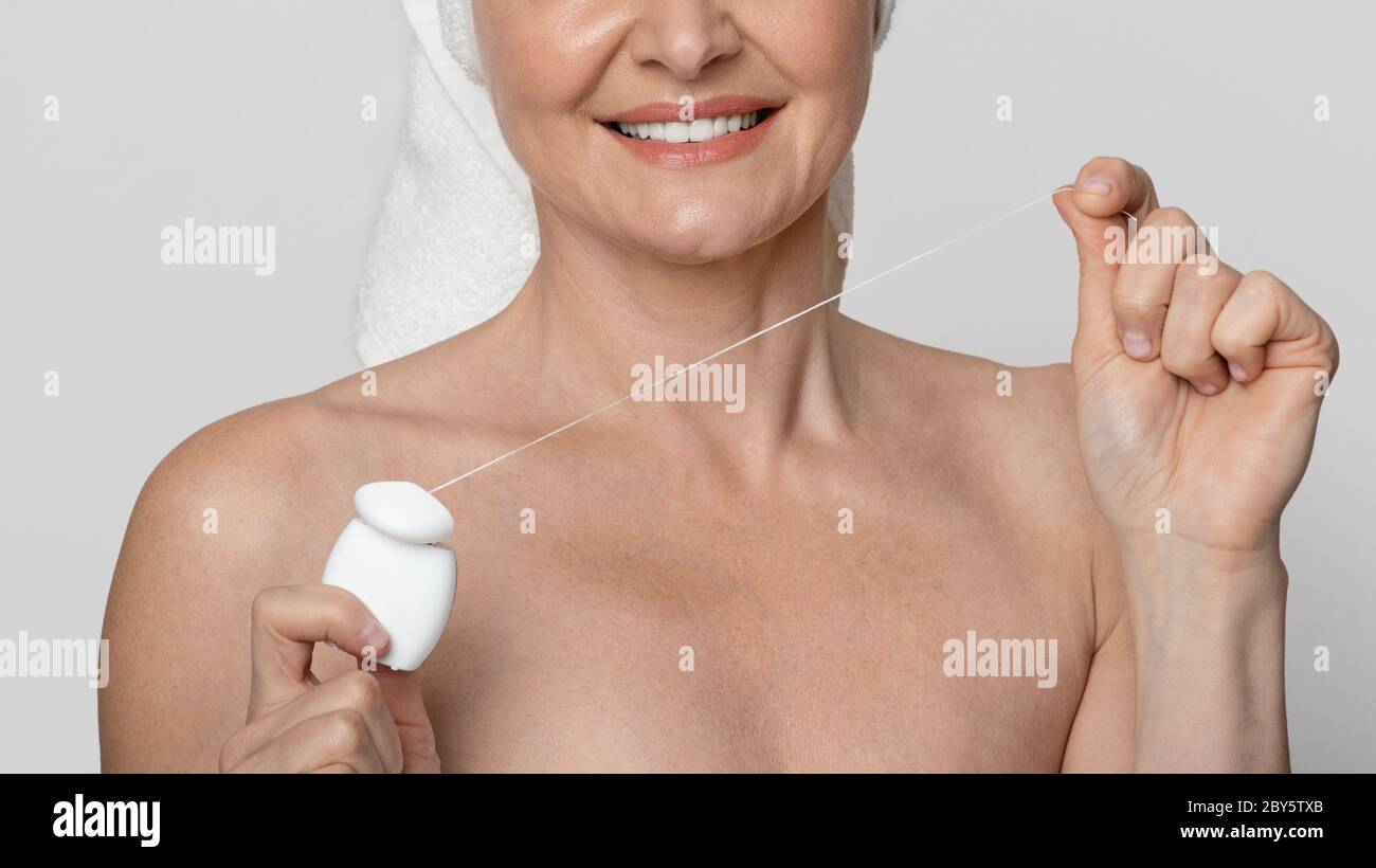 Unrecognizable middle-aged woman with white healthy teeth using dental floss Stock Photo
