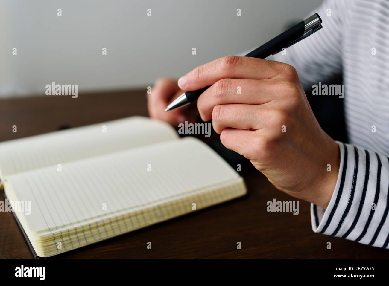 Writing by left hand in notepad. Left hander day concept Stock Photo