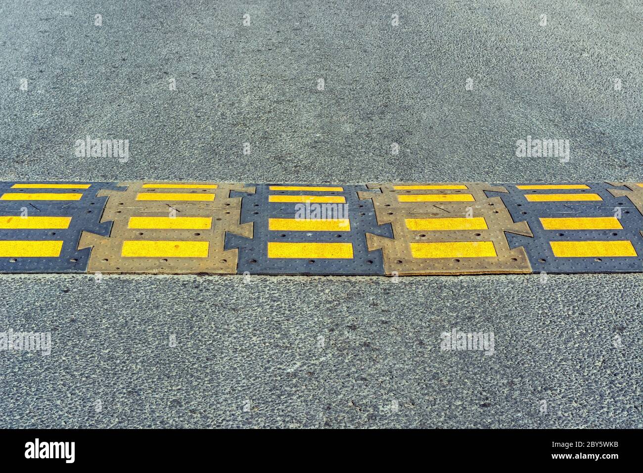 Speed bump installed on the road in front of a pedestrian crossing. Stock Photo