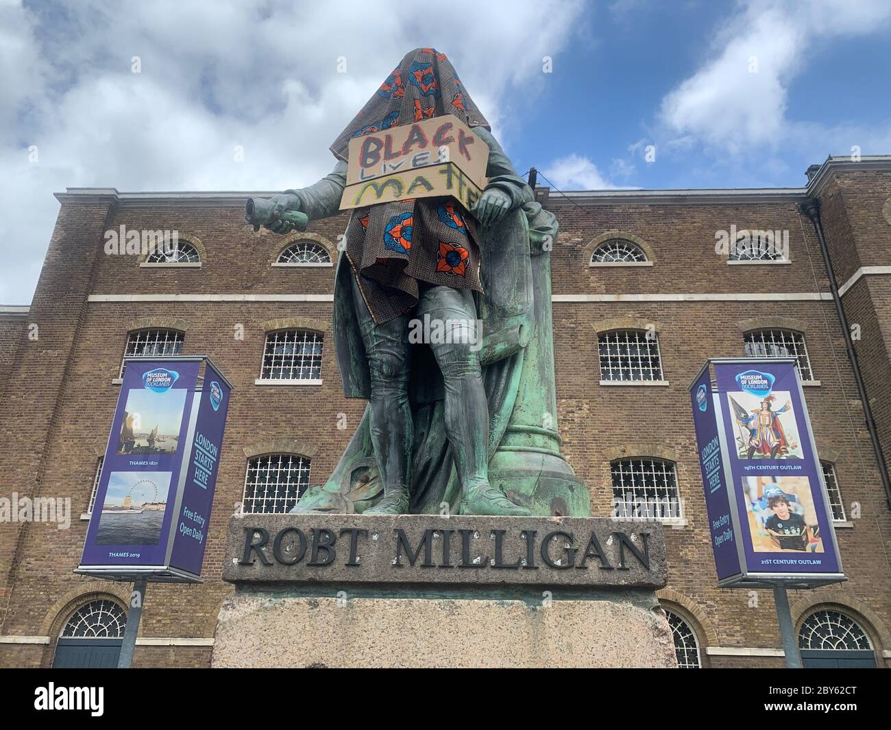 The Statue Of Robert Milligan A Noted West Indian Merchant Slaveholder And Founder Of London S Global Trade Hub West India Docks Covered In A Cloth And Black Lives Matter Sign Outside The