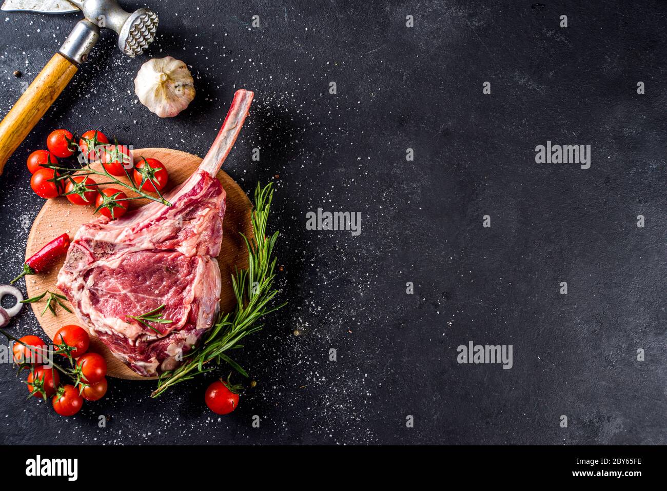Cooking meat background. Raw tomahawk steak, with spices and herbs for