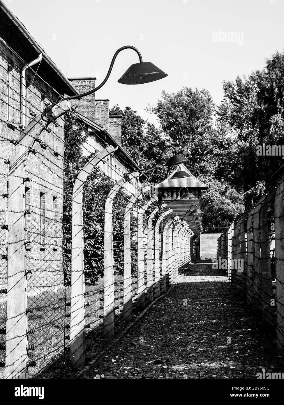 Barb wire fence with guard lamps and tower in concentration camp, Auschwitz, or Oswiecim, Poland. Stock Photo
