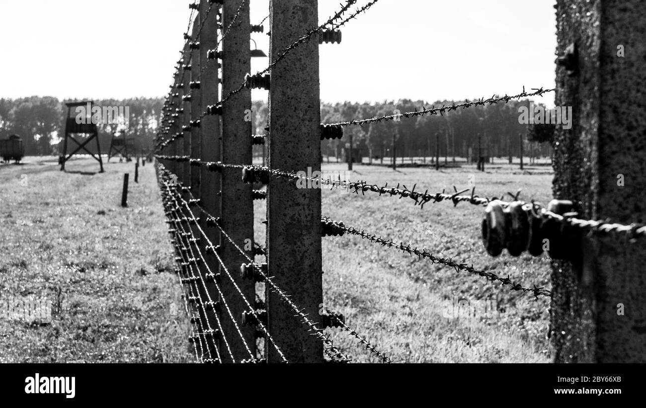 Barb wire fence and barracks in Oswiecim - Brzezinka concentration camp, German: Auschwitz - Birkenau, Poland. Black and white image. Stock Photo