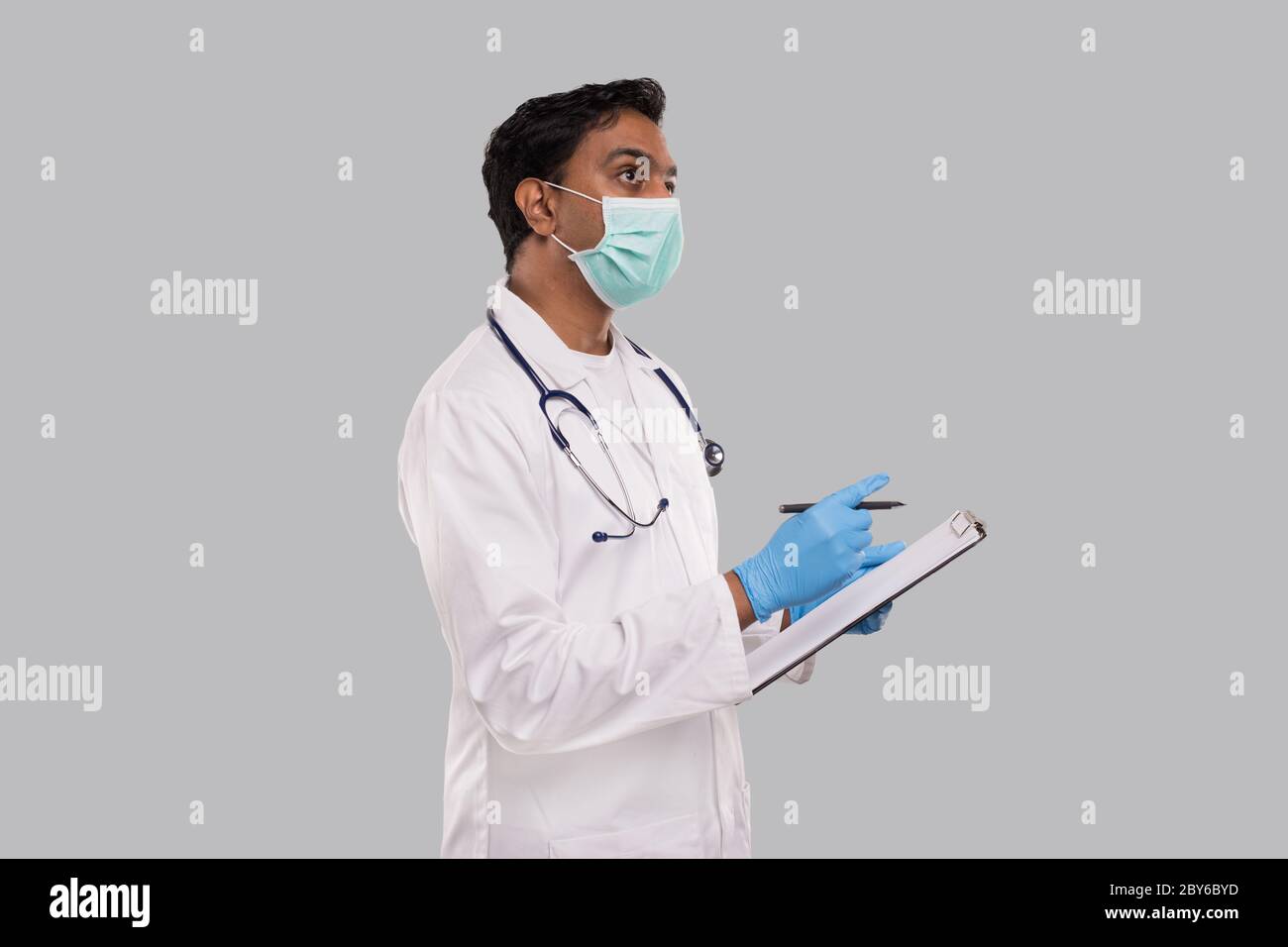 Doctor Writing Down Good Idea in Clipboard Wearing Medical Mask and Gloves. Indian Man Doctor Clipboard Isolated Stock Photo