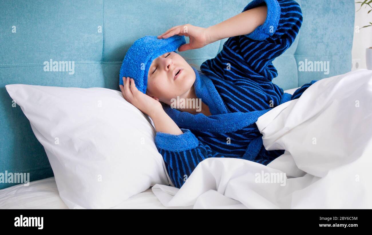 Portrait of sick woman with migraine holding cold compress on forehead