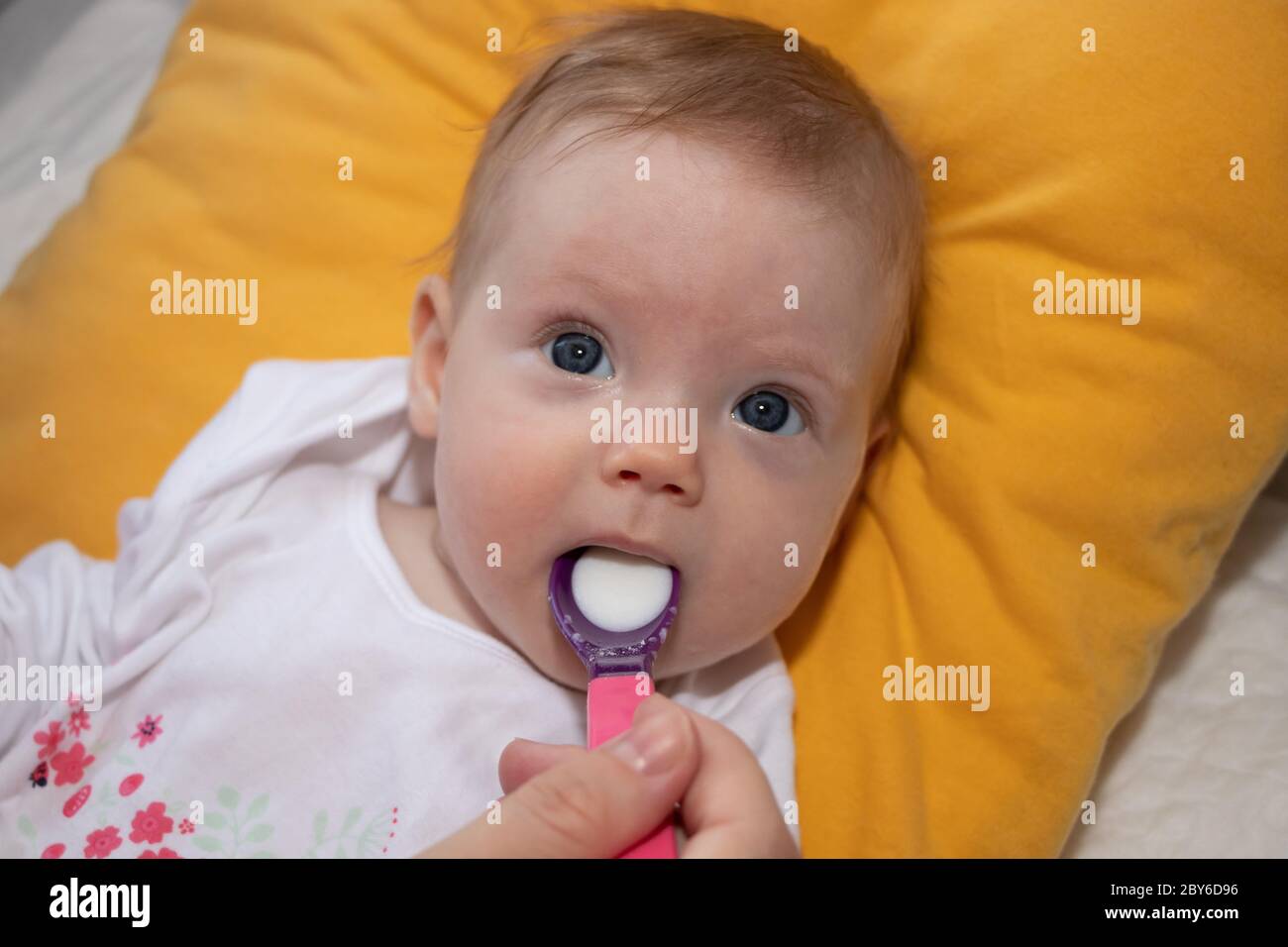 Mother feeding her baby girl with a spoon. Mother giving food to her