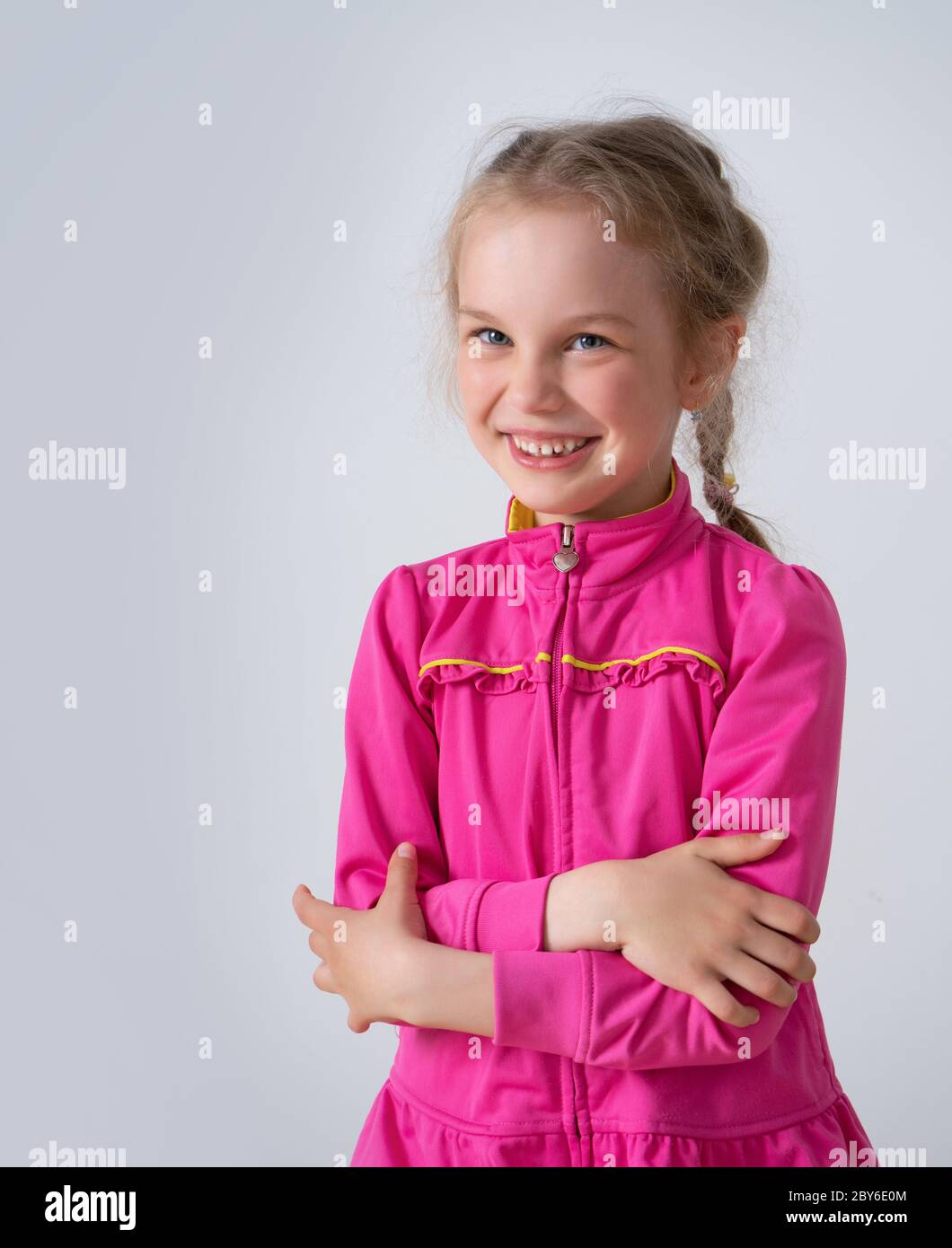 Cheerful little girl with pigtails in trendy bright pink dress smiling ...