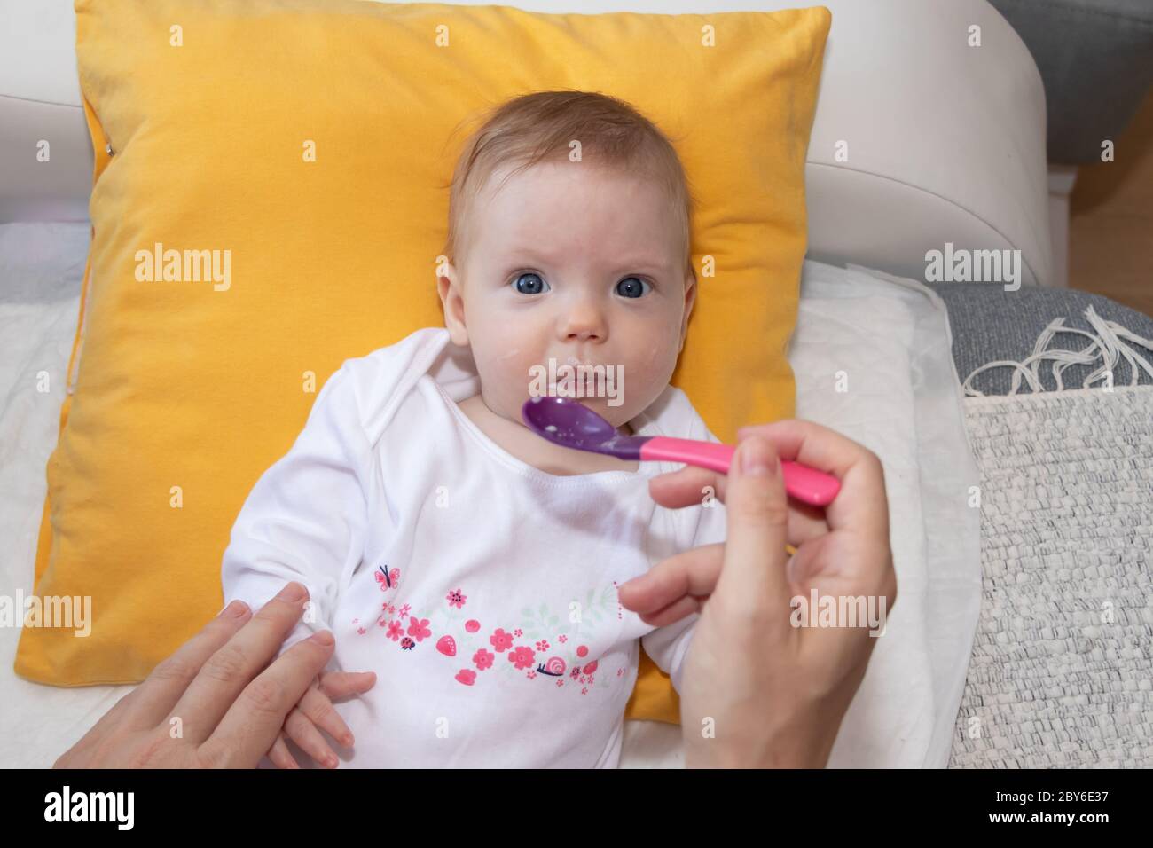 Mother feeding her baby girl with a spoon. Mother giving food to her