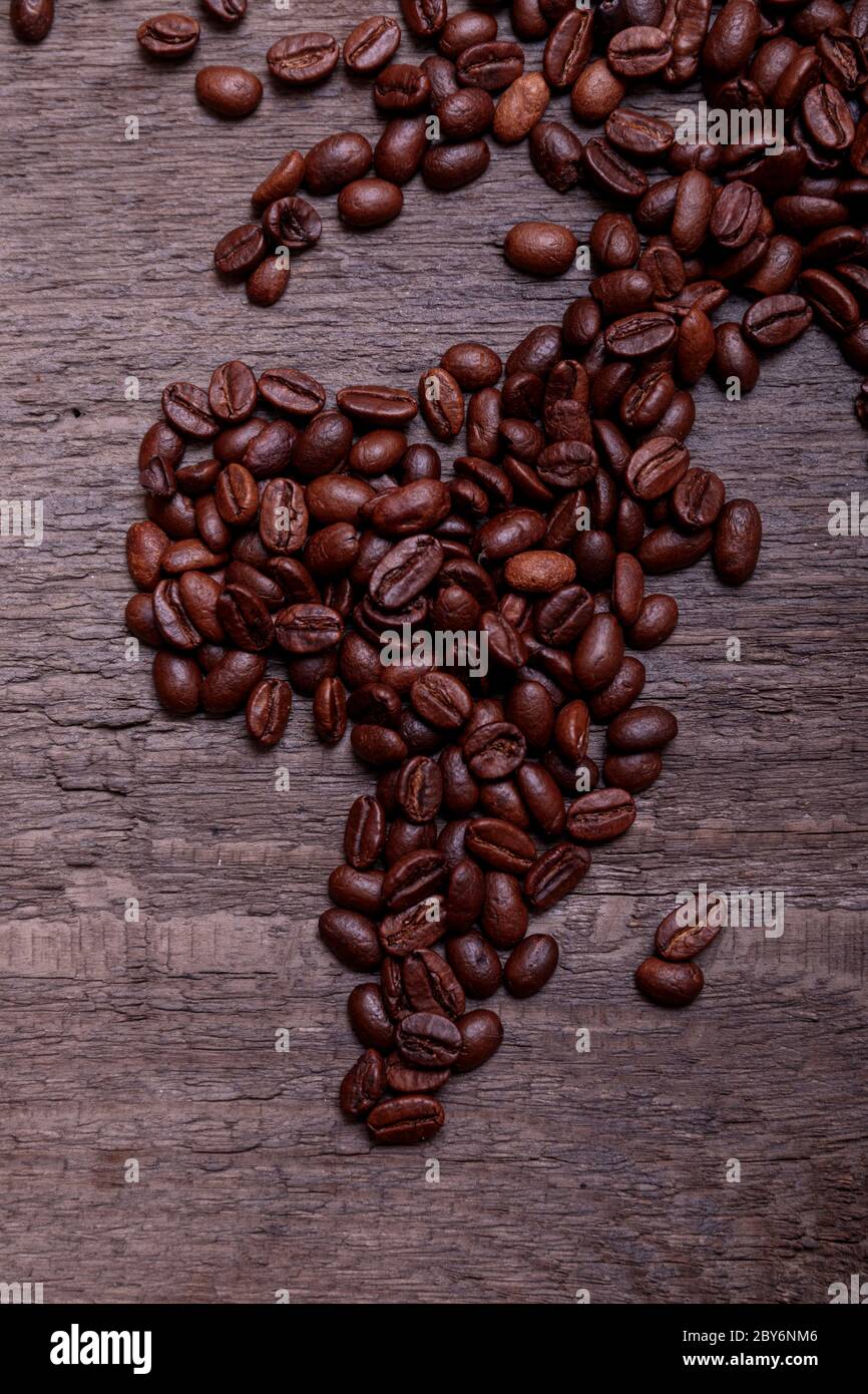 Dramatic photo of world map made of arabic roasted coffee beans on old vintage wooden table. Stock Photo