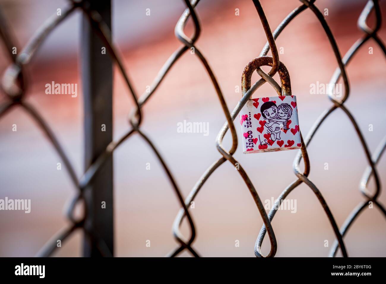 Single love lock locked to a wire fence covered in hearts and a cartoon couple in each other's arms. Photograph: Tony Taylor Stock Photo
