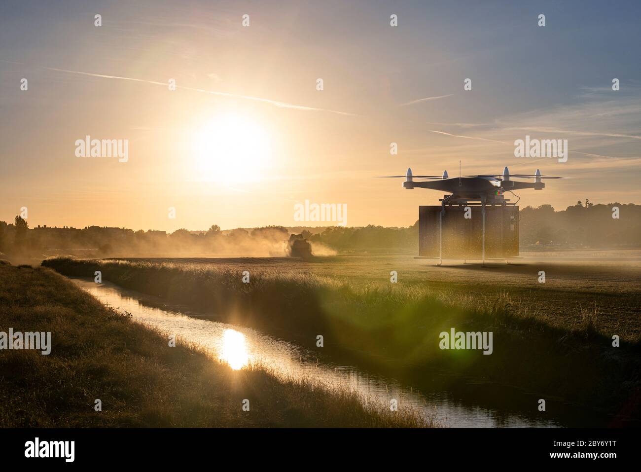 Drone delivering package over sunny farm Stock Photo