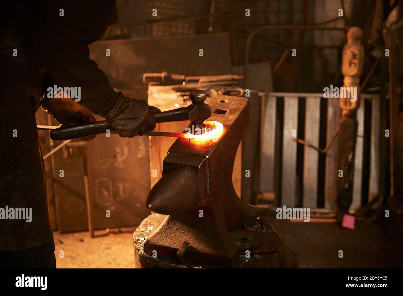 Blacksmith shaping steel on anvil in workshop Stock Photo