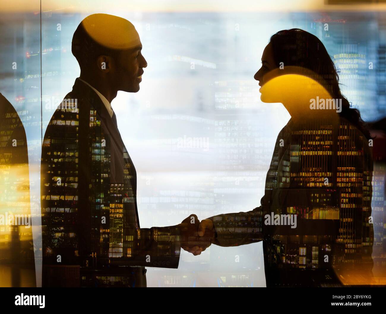 Business people shaking hands at highrise window Stock Photo