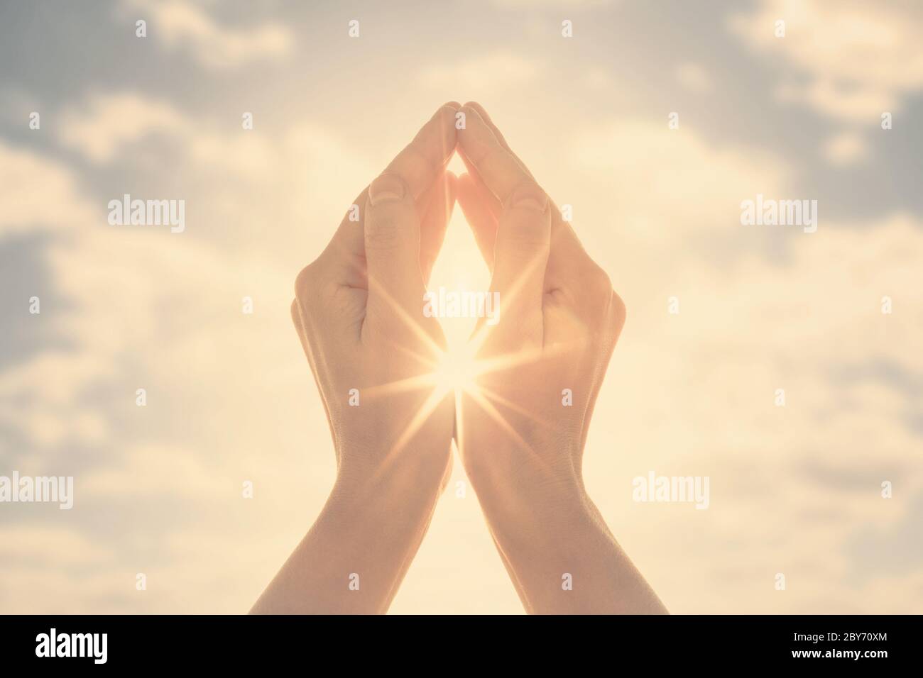 Woman hands holding the sun at dawn. Freedom and spirituality concept. Stock Photo