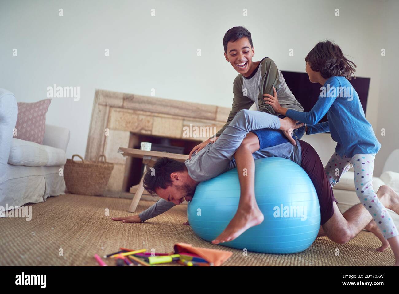Happy family playing on fitness ball in living room Stock Photo