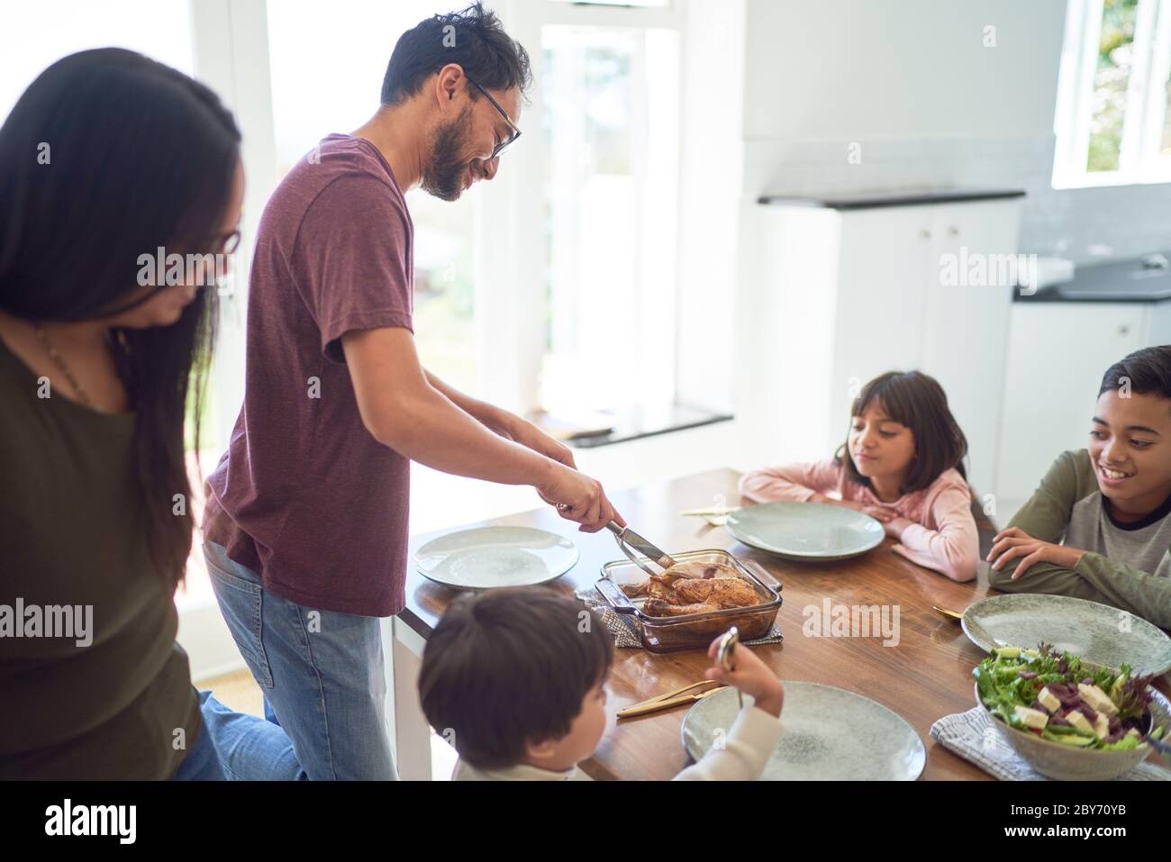 Family serving and eating dinner at dining table Stock Photo Alamy