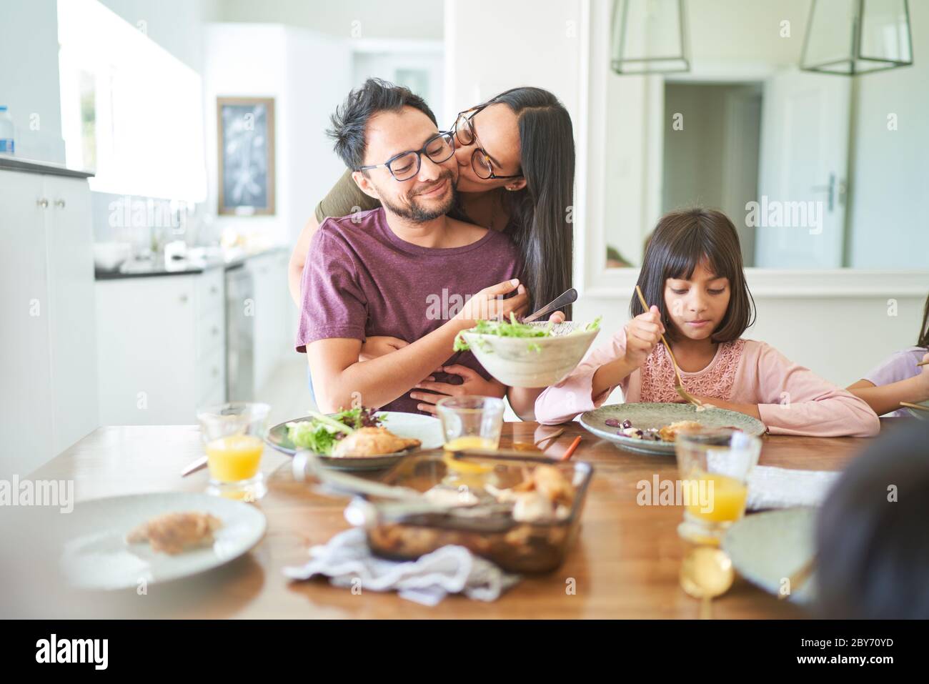 Affectionate wife kissing husband at dinner table Stock Photo