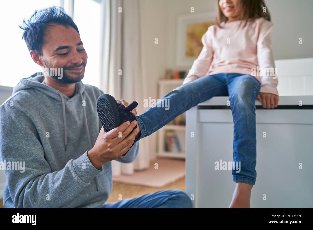 Father helping daughter put on shoes Stock Photo