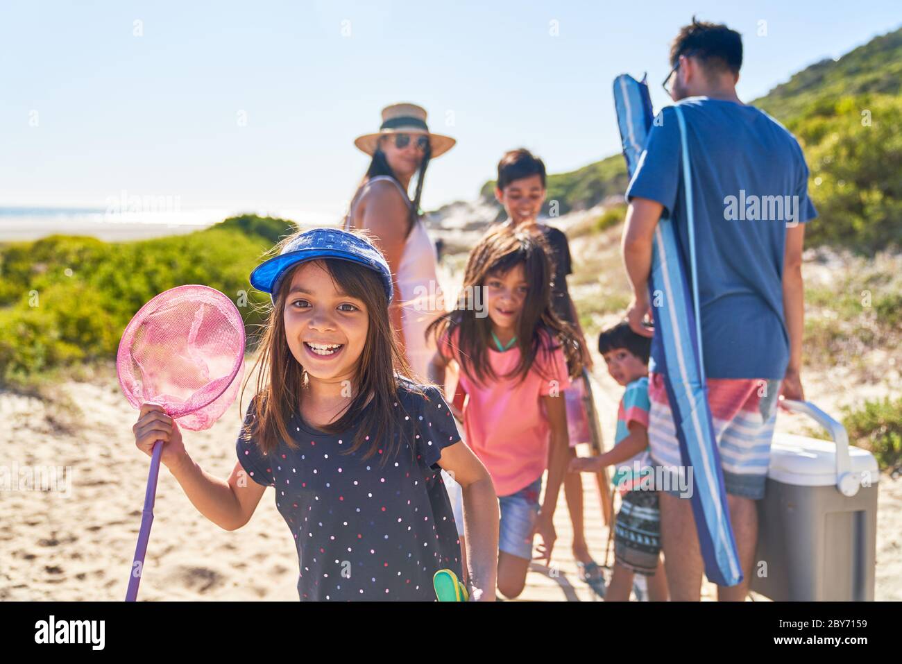 Portrait happy girl with butterfly net on sunny beach with family Stock Photo