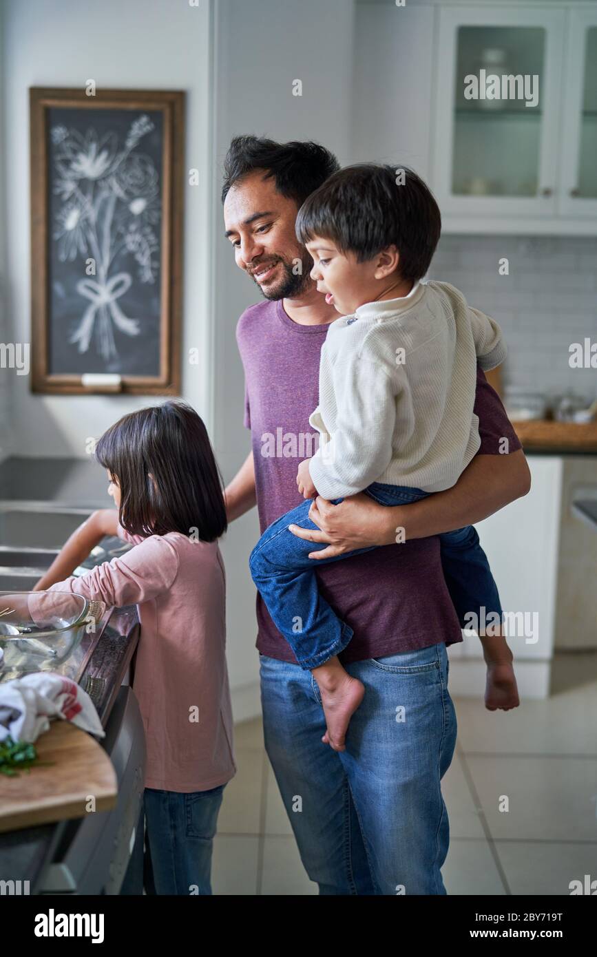 Father and kids doing dishes in kitchen Stock Photo