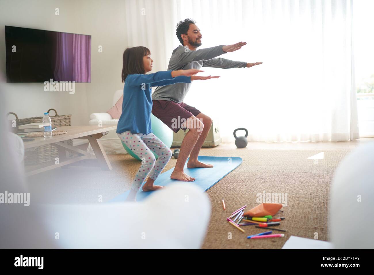 Father and daughter exercising in living room Stock Photo