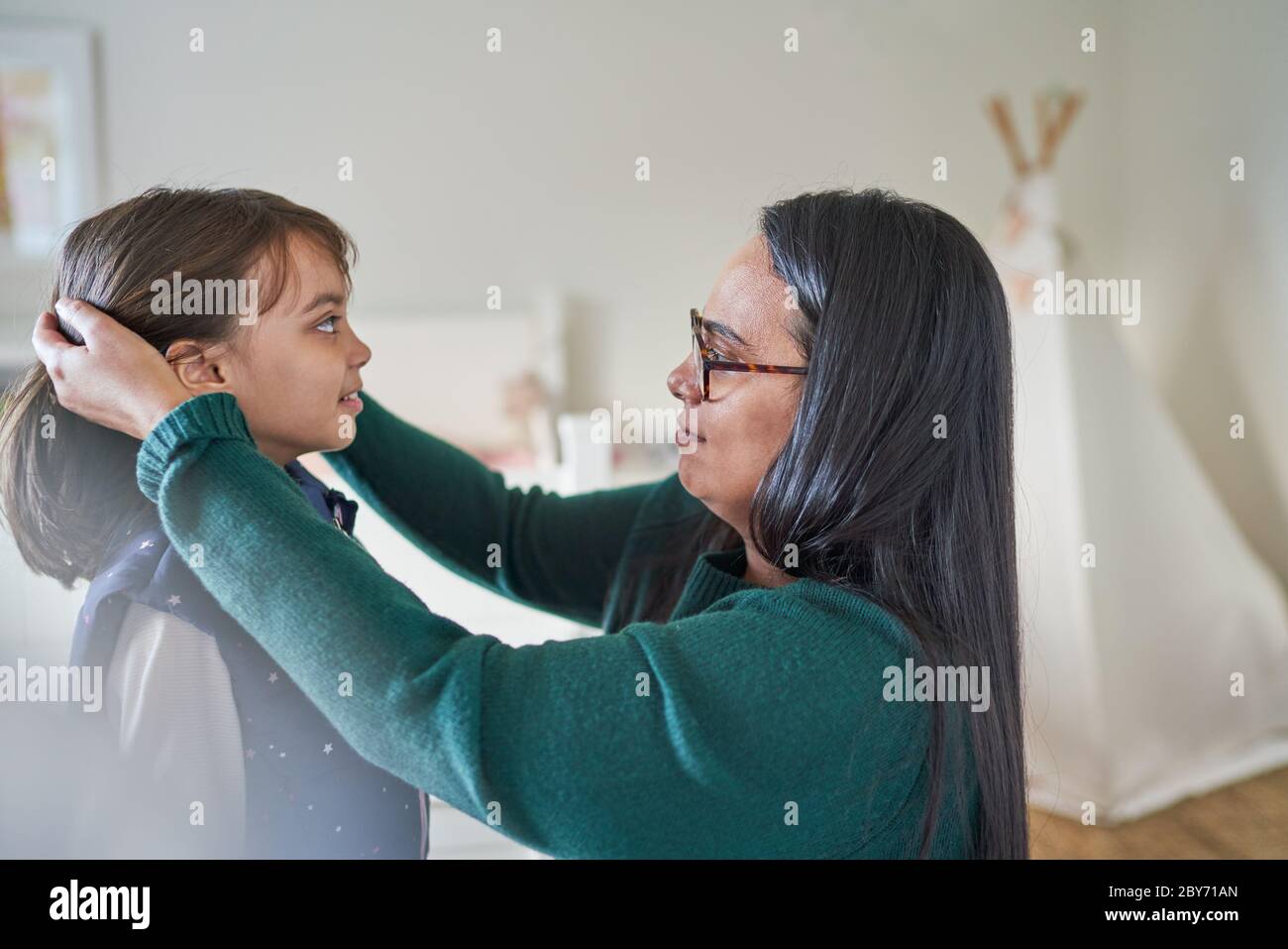 Mother helping daughter fix hair Stock Photo