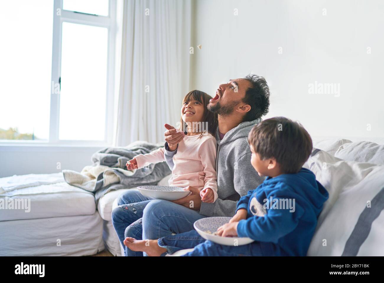 Playful family eating popcorn on sofa Stock Photo