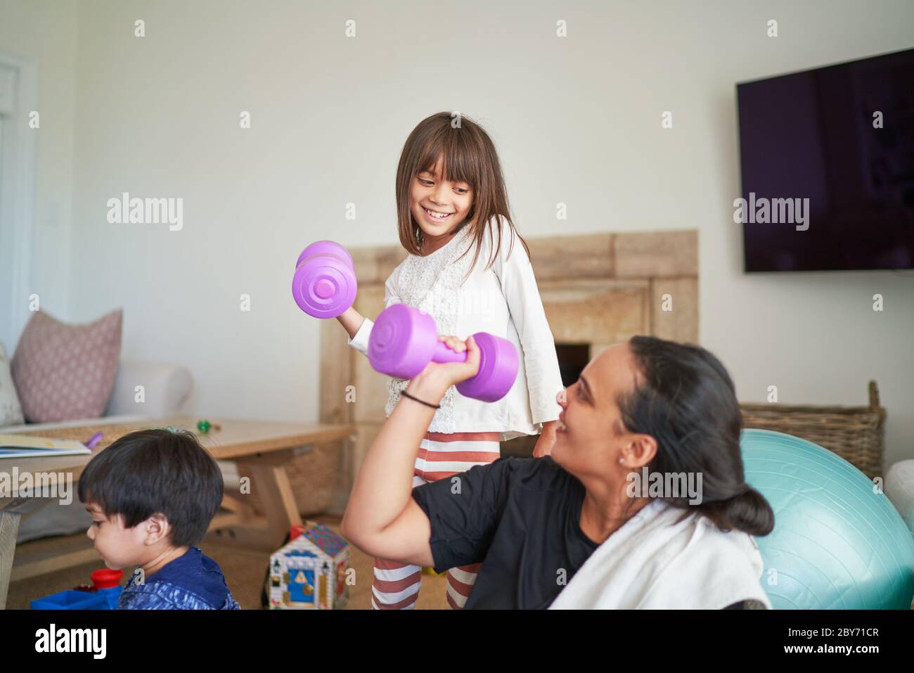 Mother and daughter exercising with dumbbells in living room Stock Photo