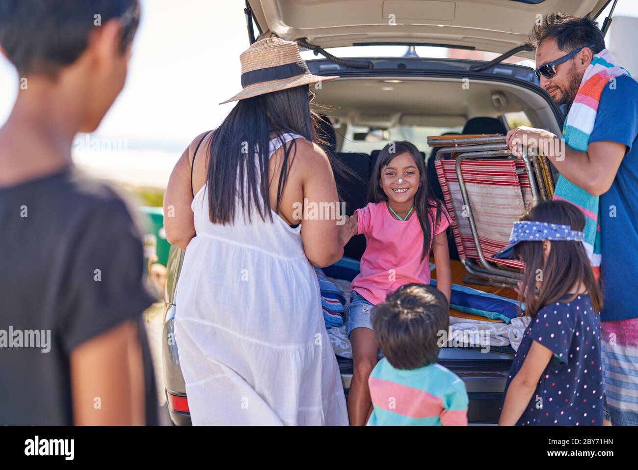 Happy girl with sunscreen on nose with family at car Stock Photo