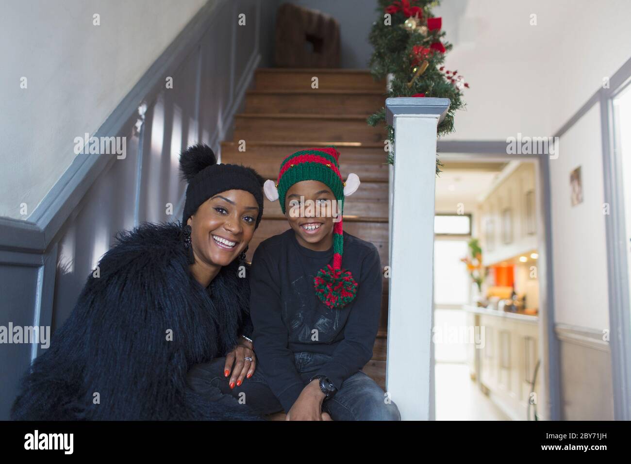 Portrait happy mother and son wearing Christmas hats on staircase Stock Photo